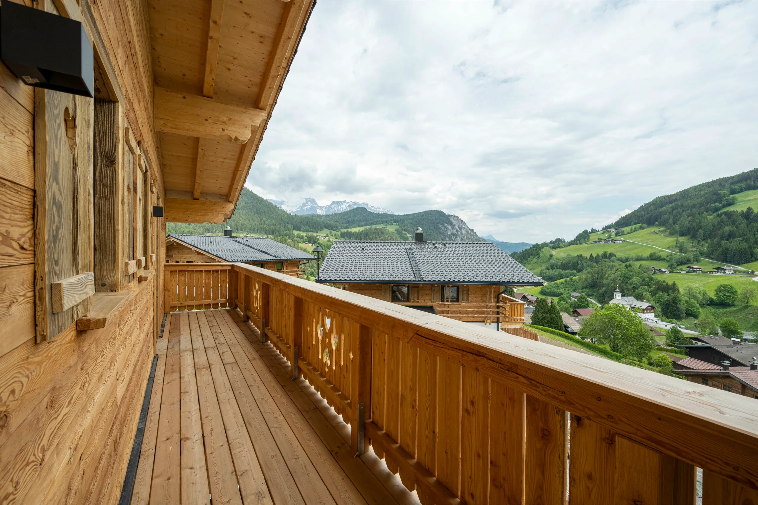 Holzbalkon eines Chalets mit Blick über das Tal und die Berge