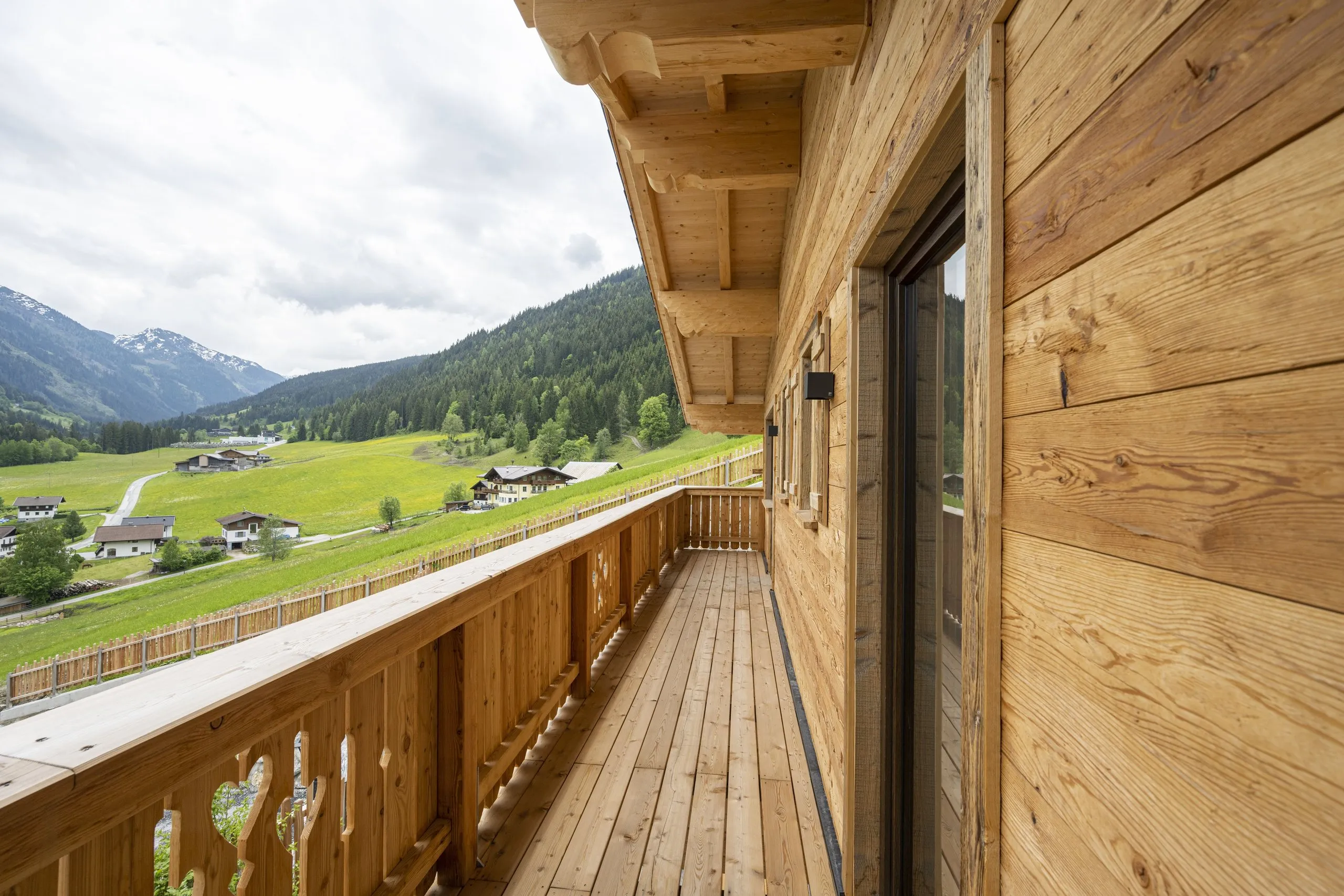Langer Holzbalkon mit Blick über Wiesen ins Tal
