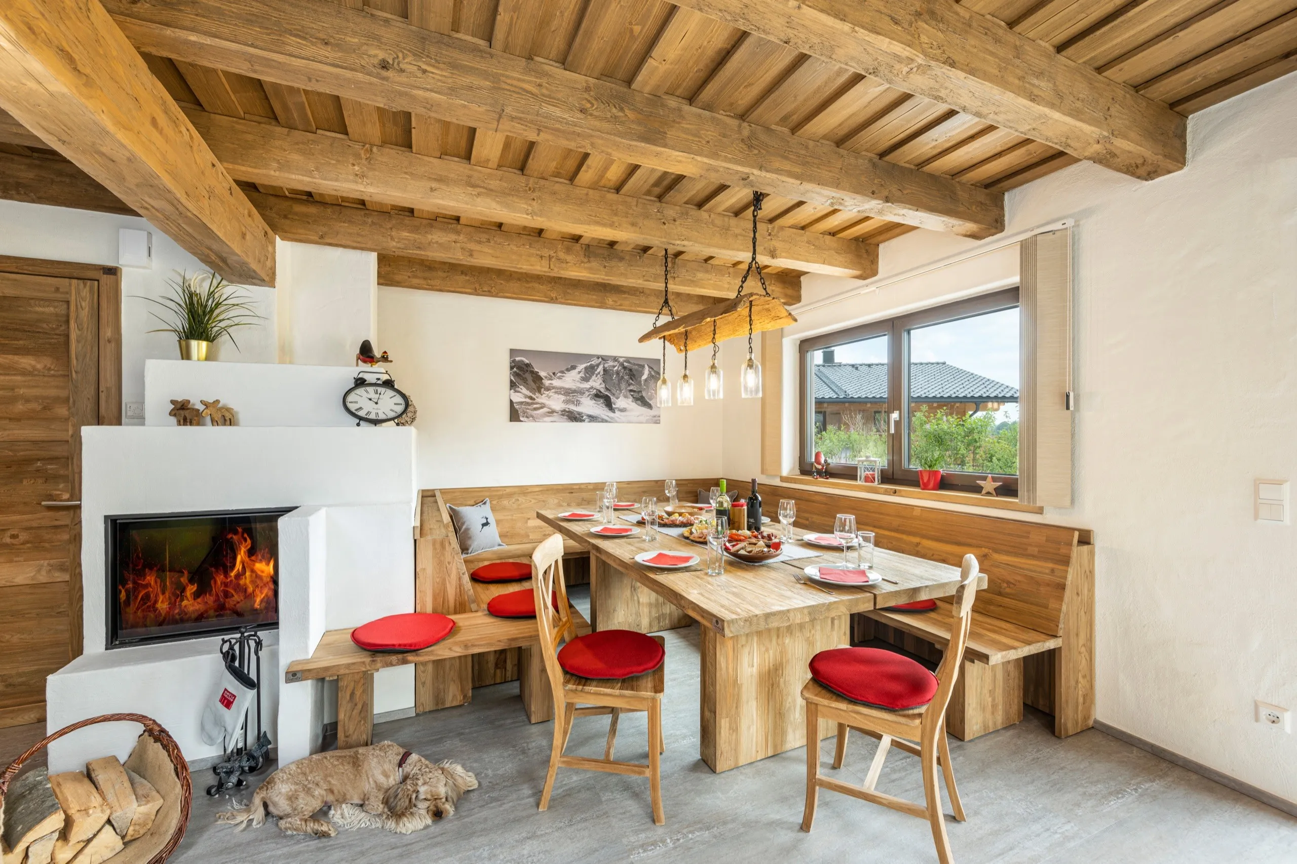 Essbereich mit Kamin und Holztisch, davor liegt ein Hund
