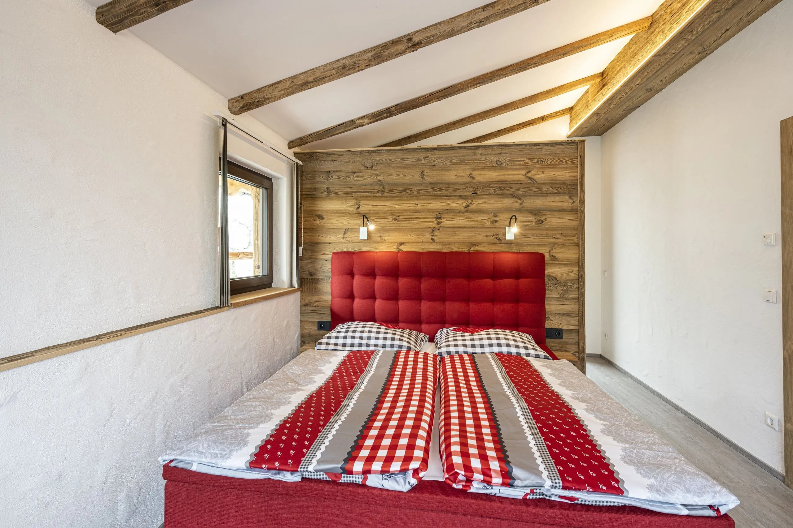 Elternschlafzimmer mit rotem Doppelbett unter der Dachschräge