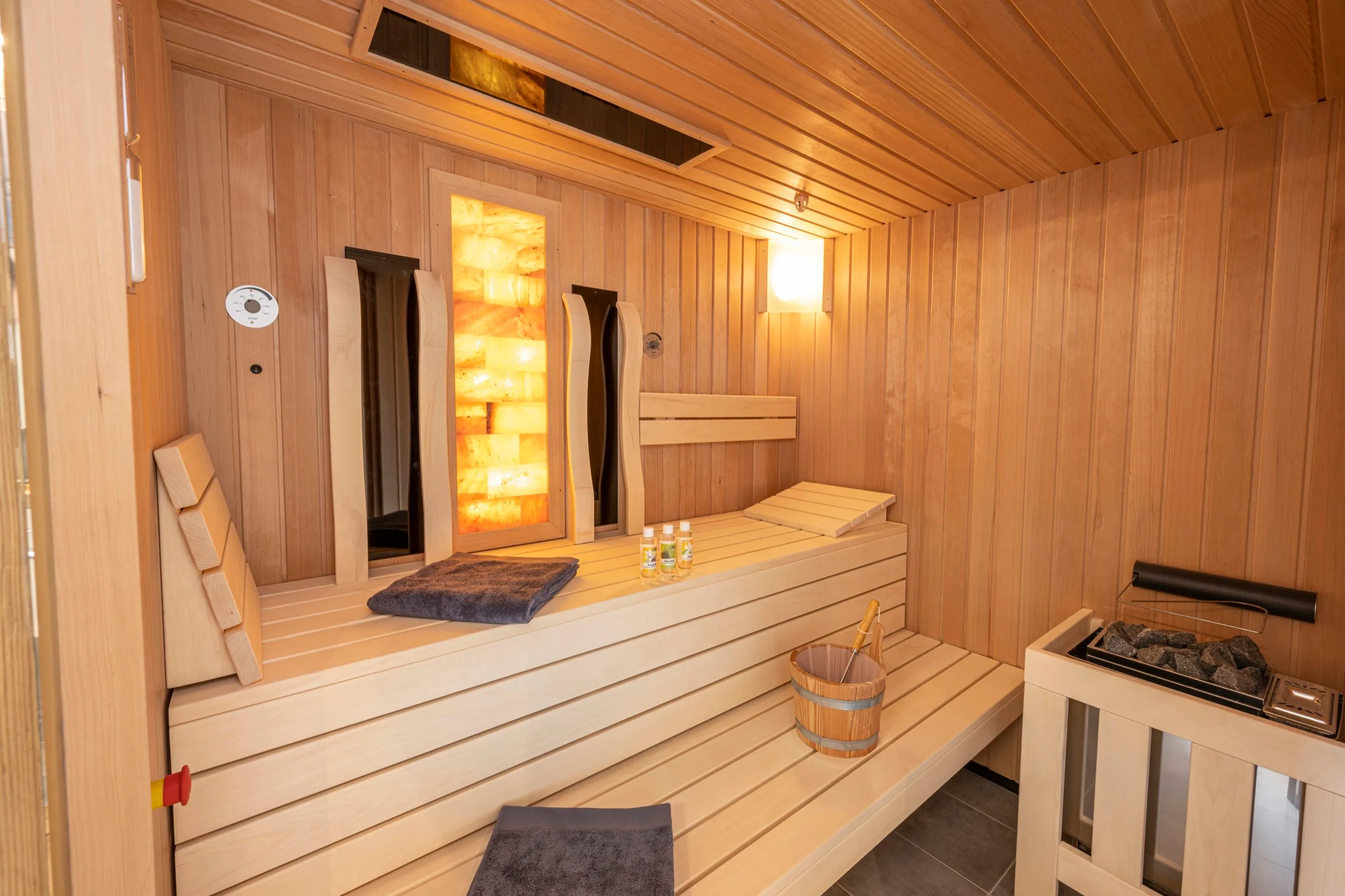 Private Sauna mit Holzbänken und beleuchteter Salzsteinwand