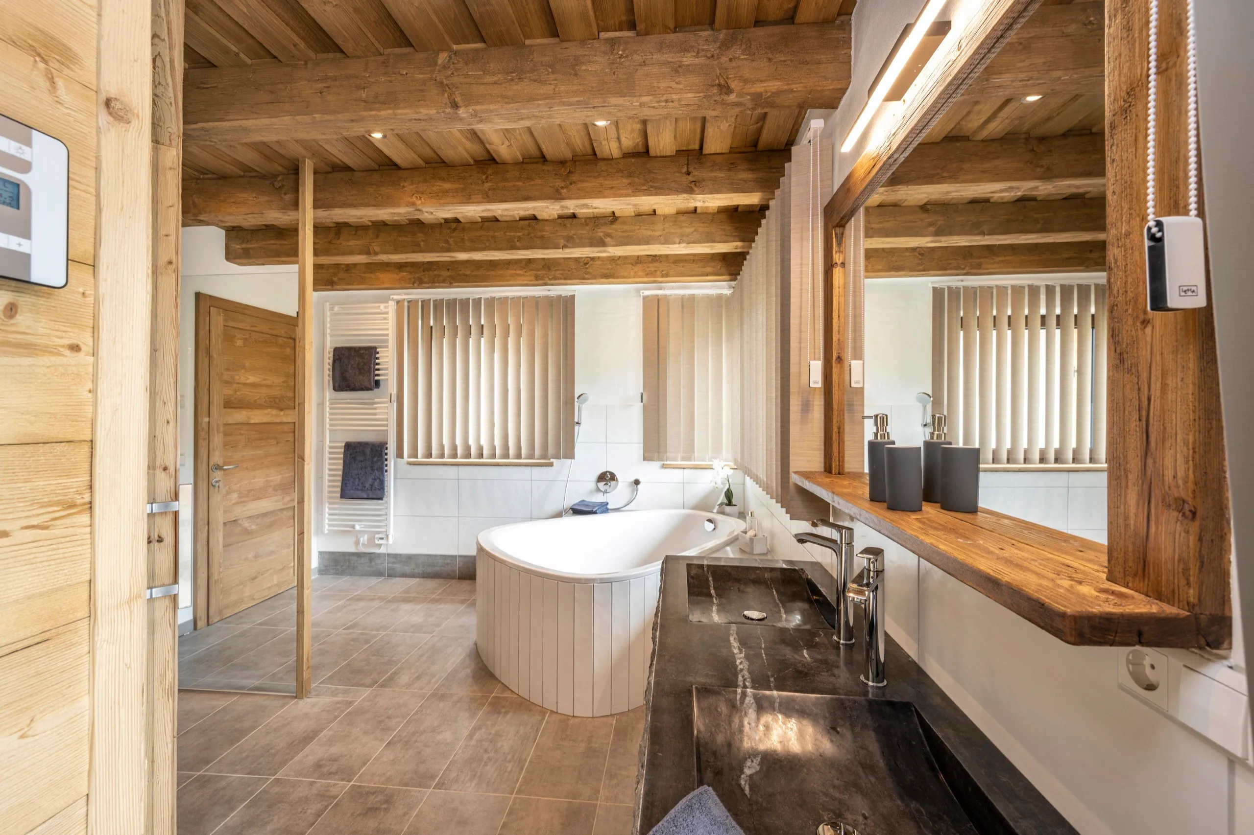 Wellnessbad mit freistehender Badewanne und Holzwaschtisch