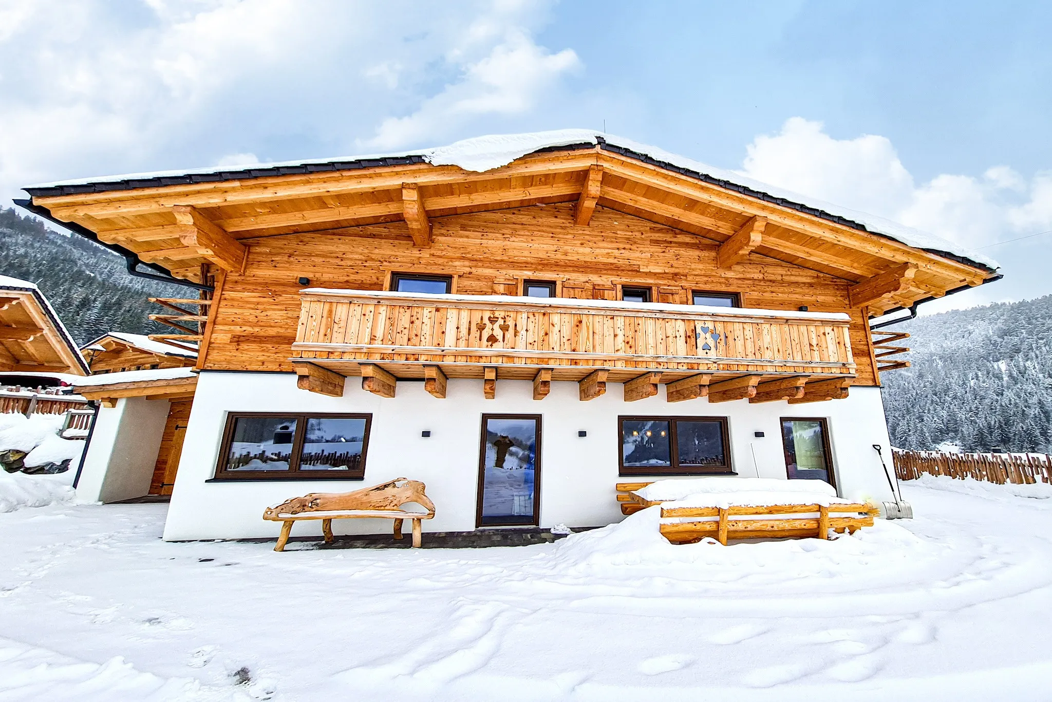 Verschneites Chalet mit Holzbalkon unter blauem Himmel