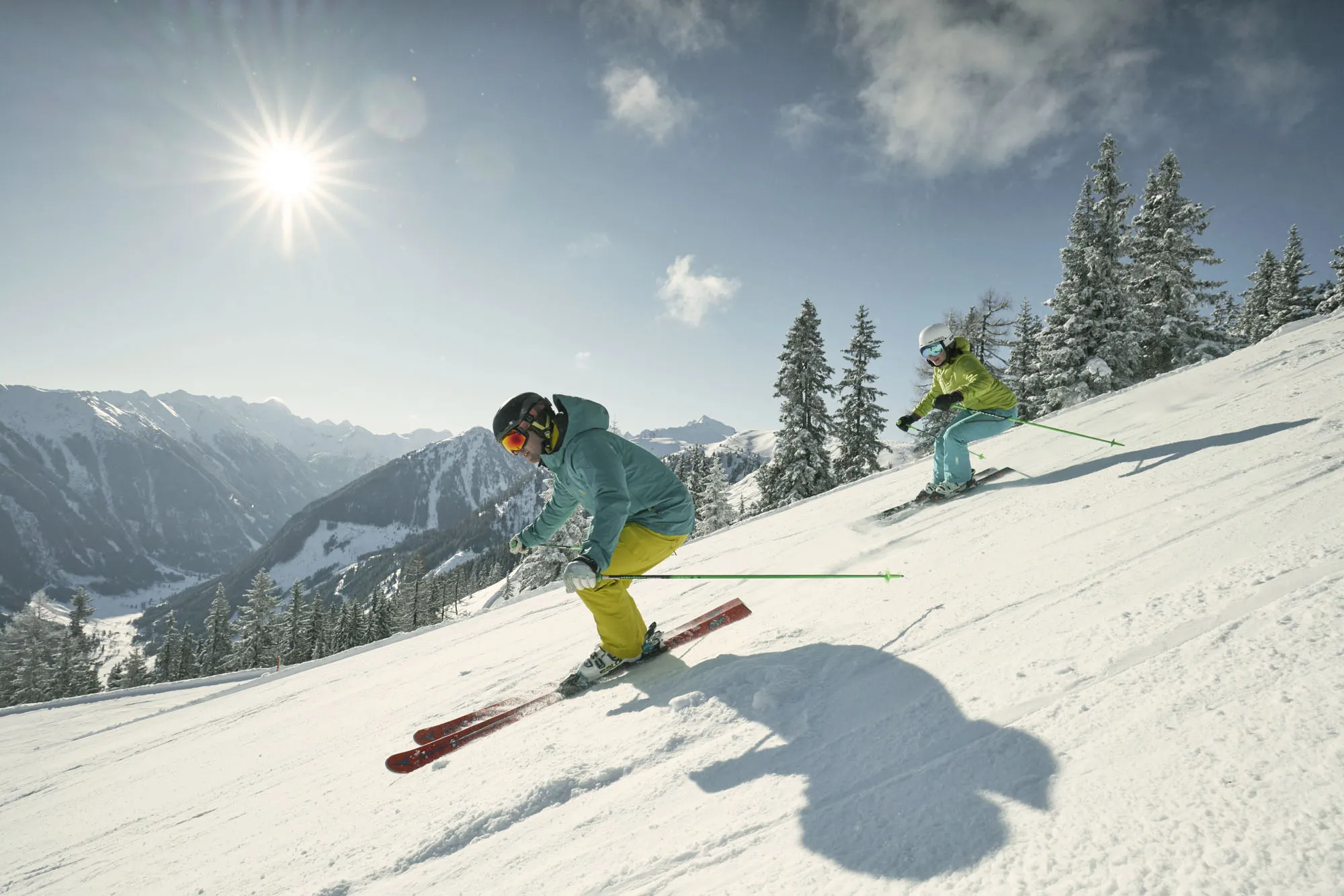 Zwei Skifahrer auf einer sonnigen Piste